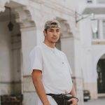Stylish young man in casual streetwear stands confidently outdoors, showcasing modern fashion.
